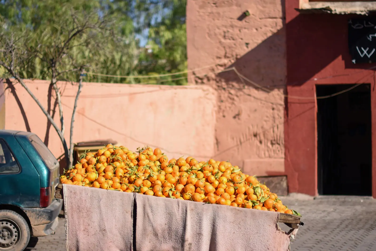 Street cart piled with oranges against red ochre walls