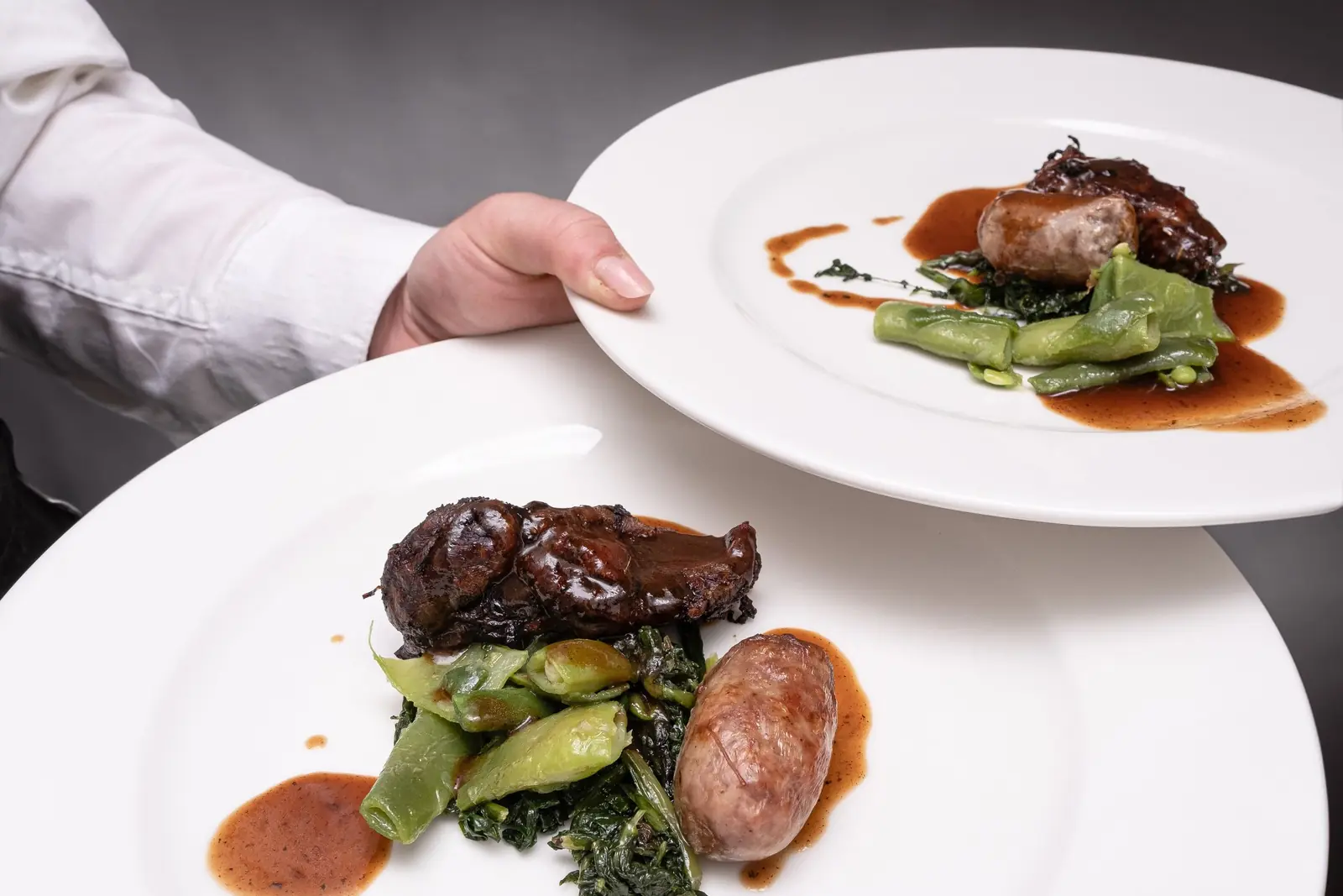Chef setting down two finely plated dishes