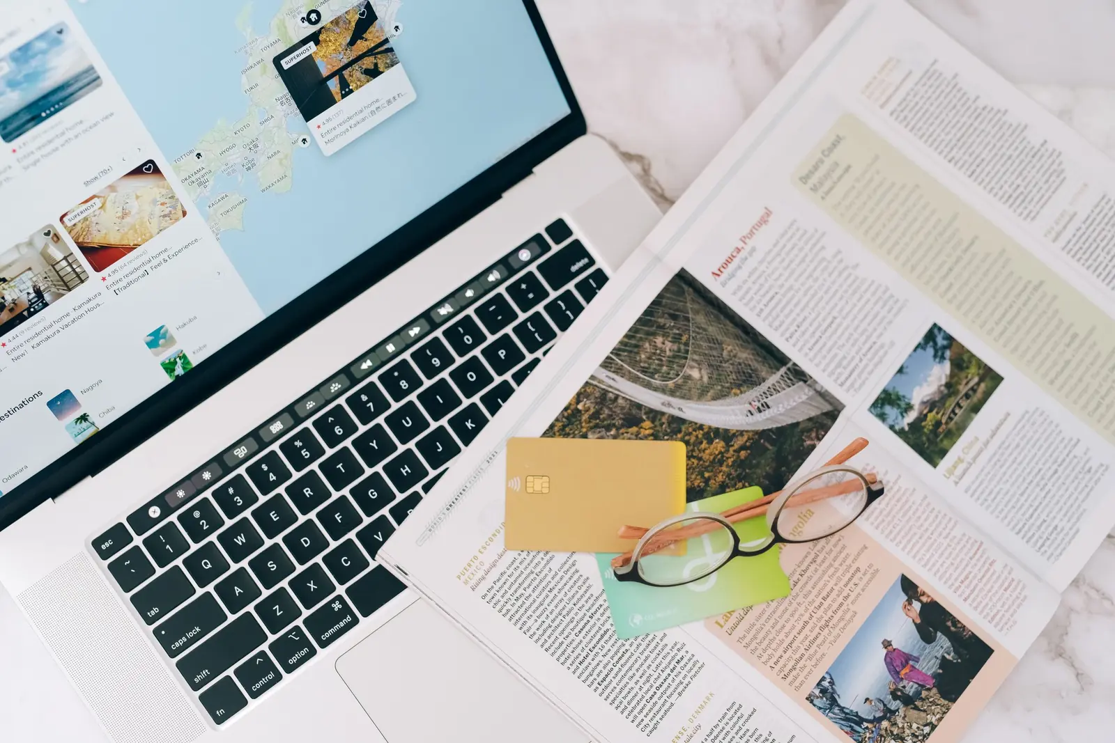 Laptop, notebook and travel papers on a desk while planning a trip