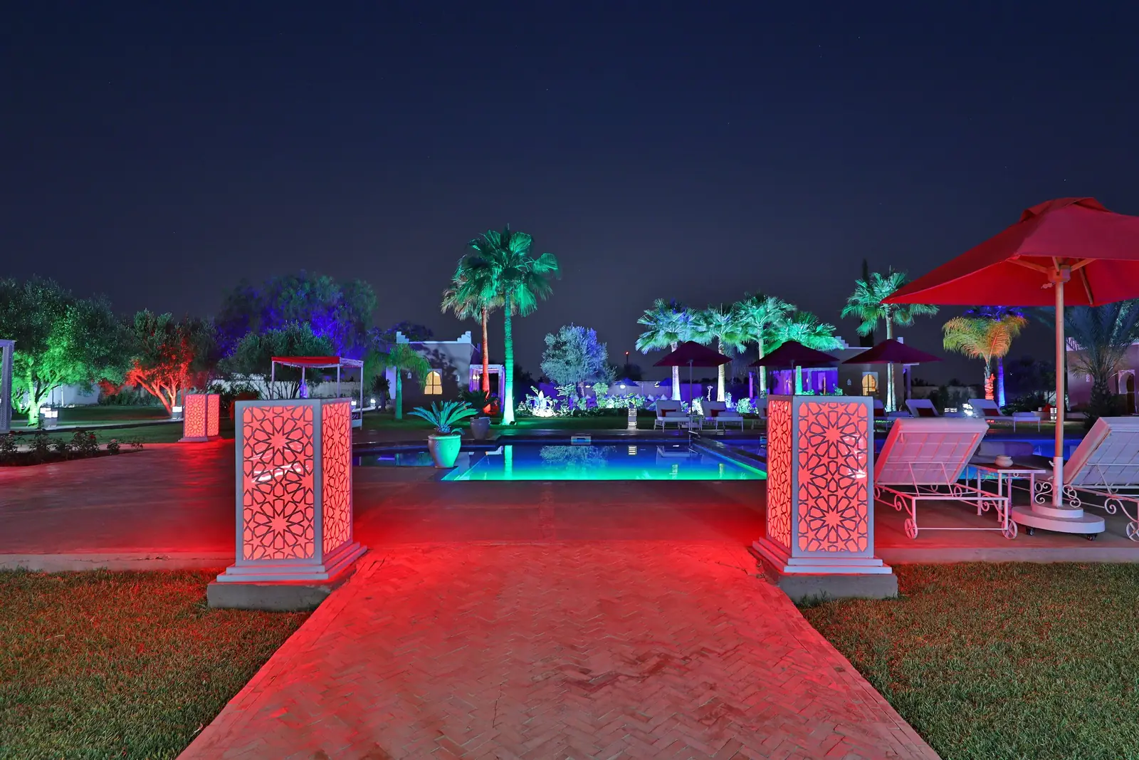 Jardin et piscine éclairés de nuit au Domaine Beldi, Marrakech