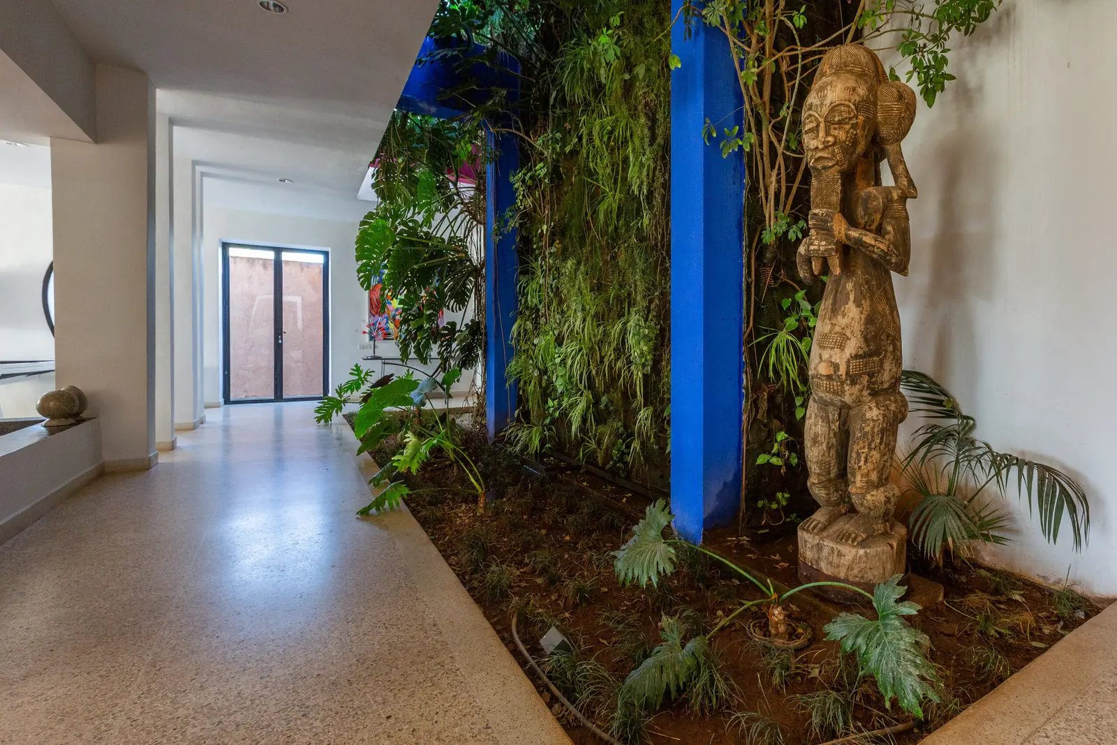 Mur végétal, portes bleues et statue au Palais Melody, Marrakech