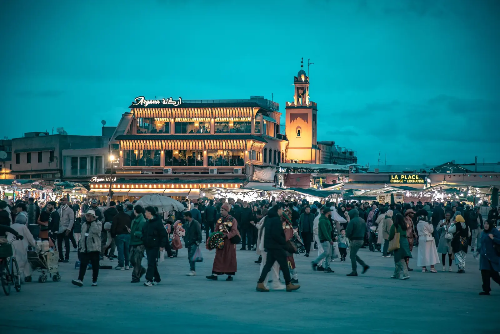 Crowd on Jemaa el-Fna at dusk, with the lit cafés around the square