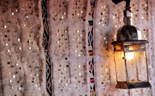 Lit lantern against a studded Moroccan wall