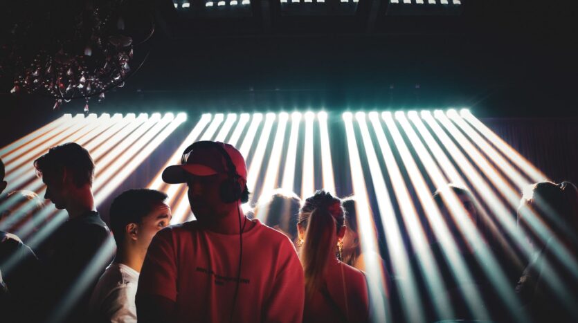 Dance floor of a Marrakech nightclub at night, DJ playing under beams of stage light