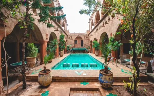 Patio d'un riad traditionnel avec bassin, plantes et arcades