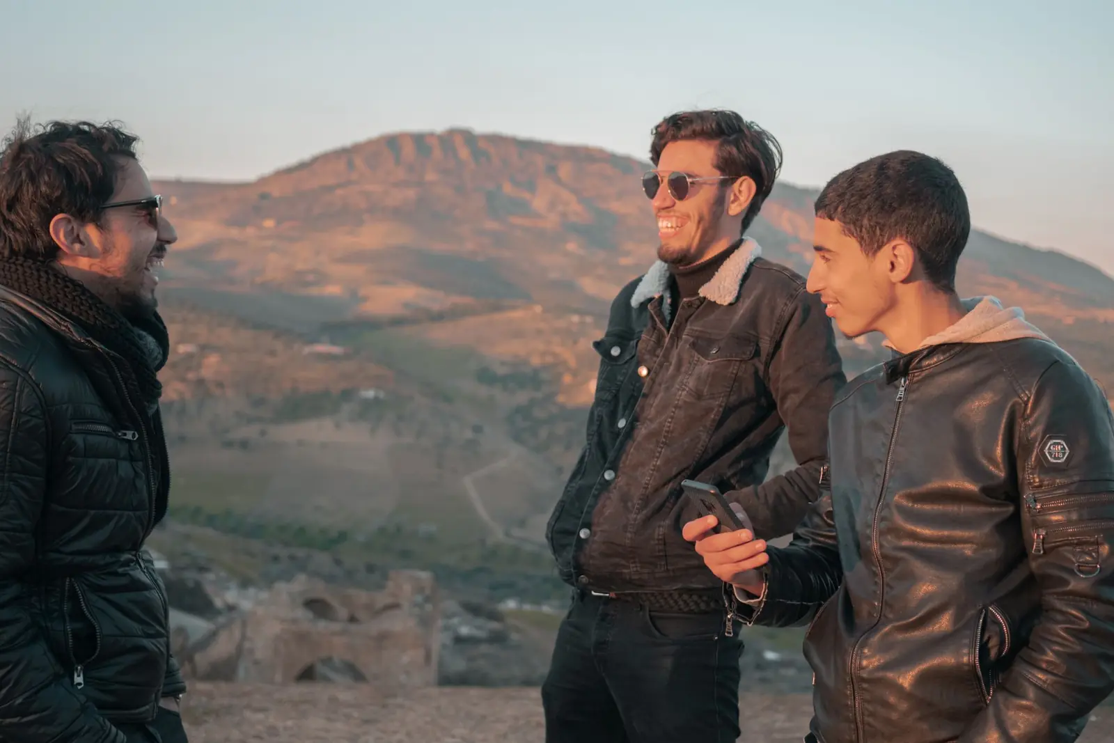 Three young friends laughing with dry mountains behind them