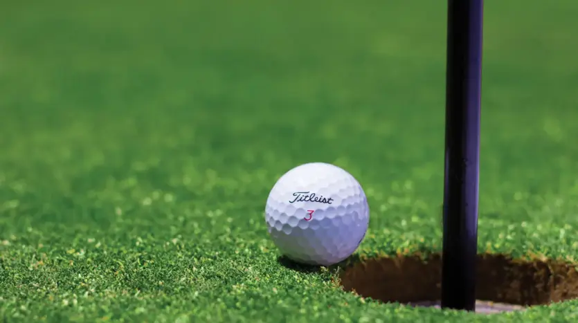 Golf ball resting beside the hole on a putting green