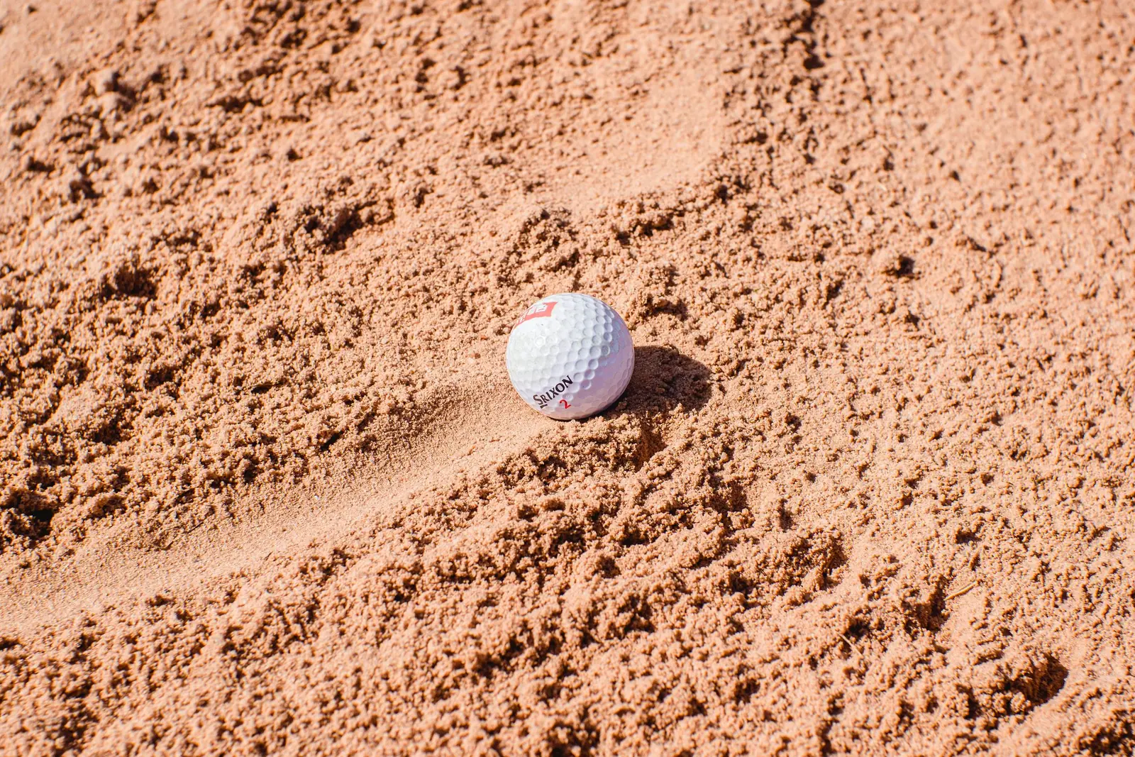 Golf ball resting in a sand bunker