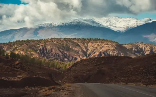 Road through the High Atlas below snow-dusted peaks
