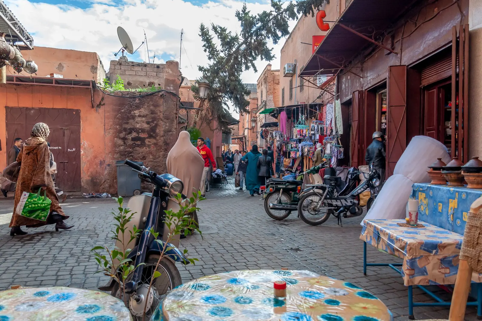 Everyday medina street with passers-by in djellabas and parked mopeds