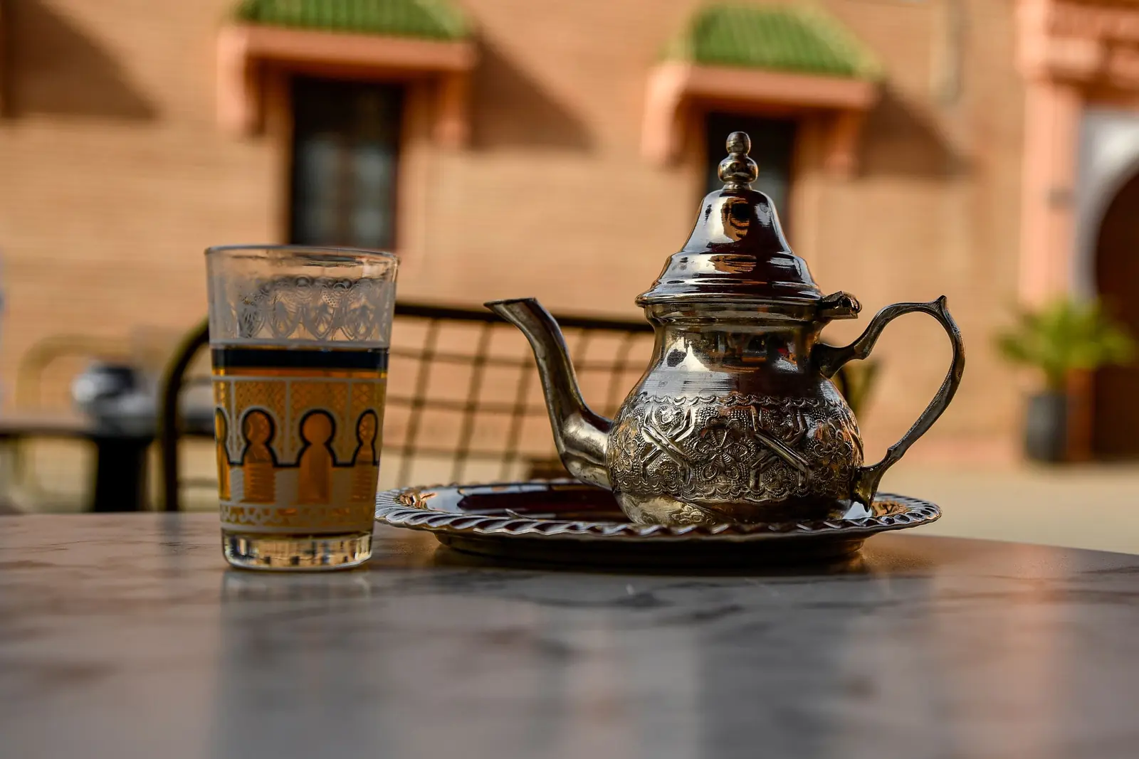 Glass of mint tea and a silver teapot on a café table