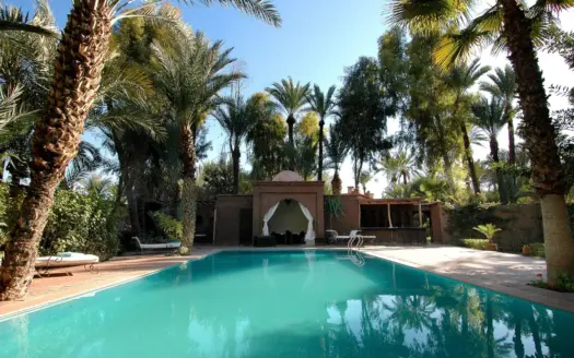 Piscine d'hôtel entourée de palmiers et d'un pavillon