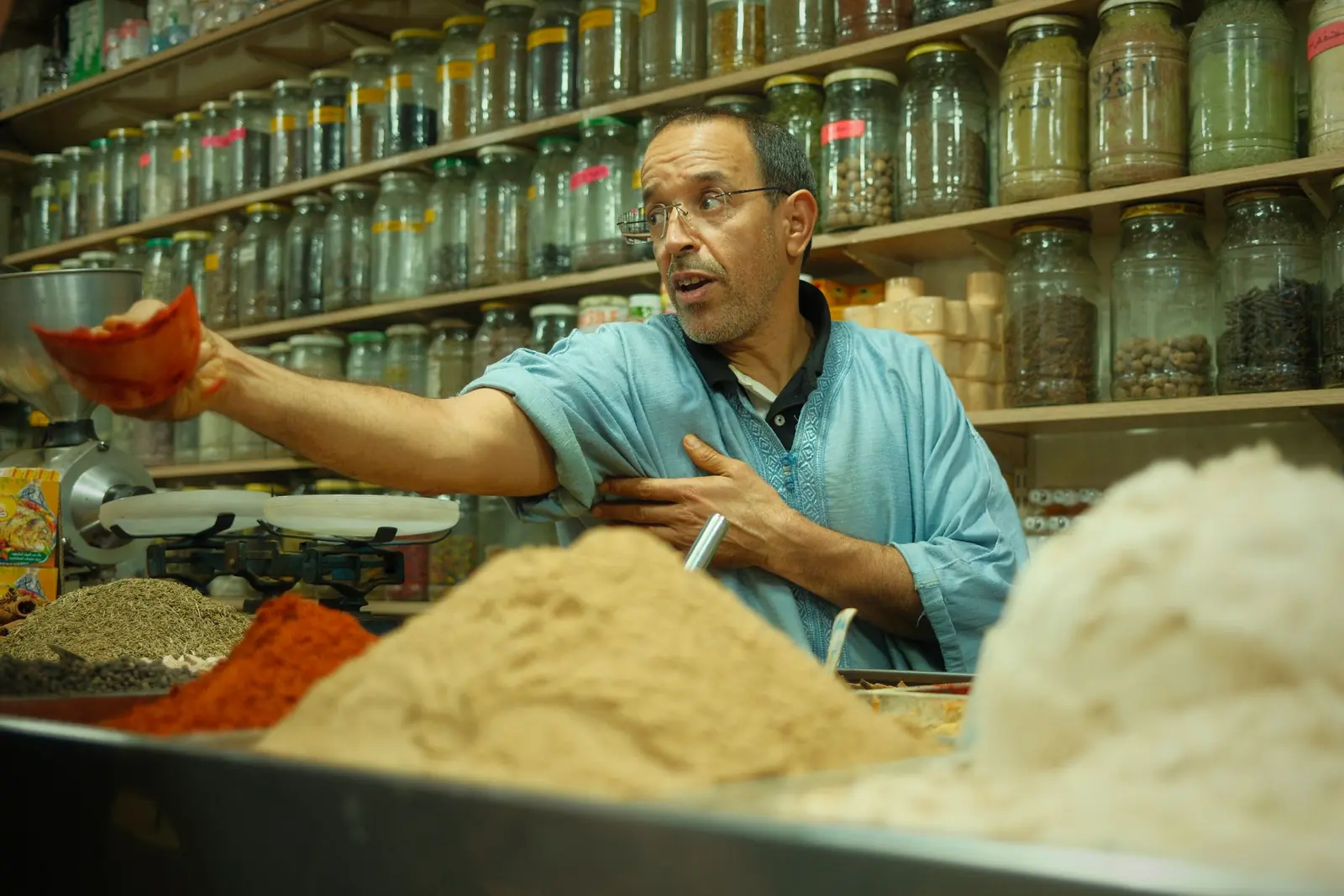 Spice seller serving from heaped spices in his shop