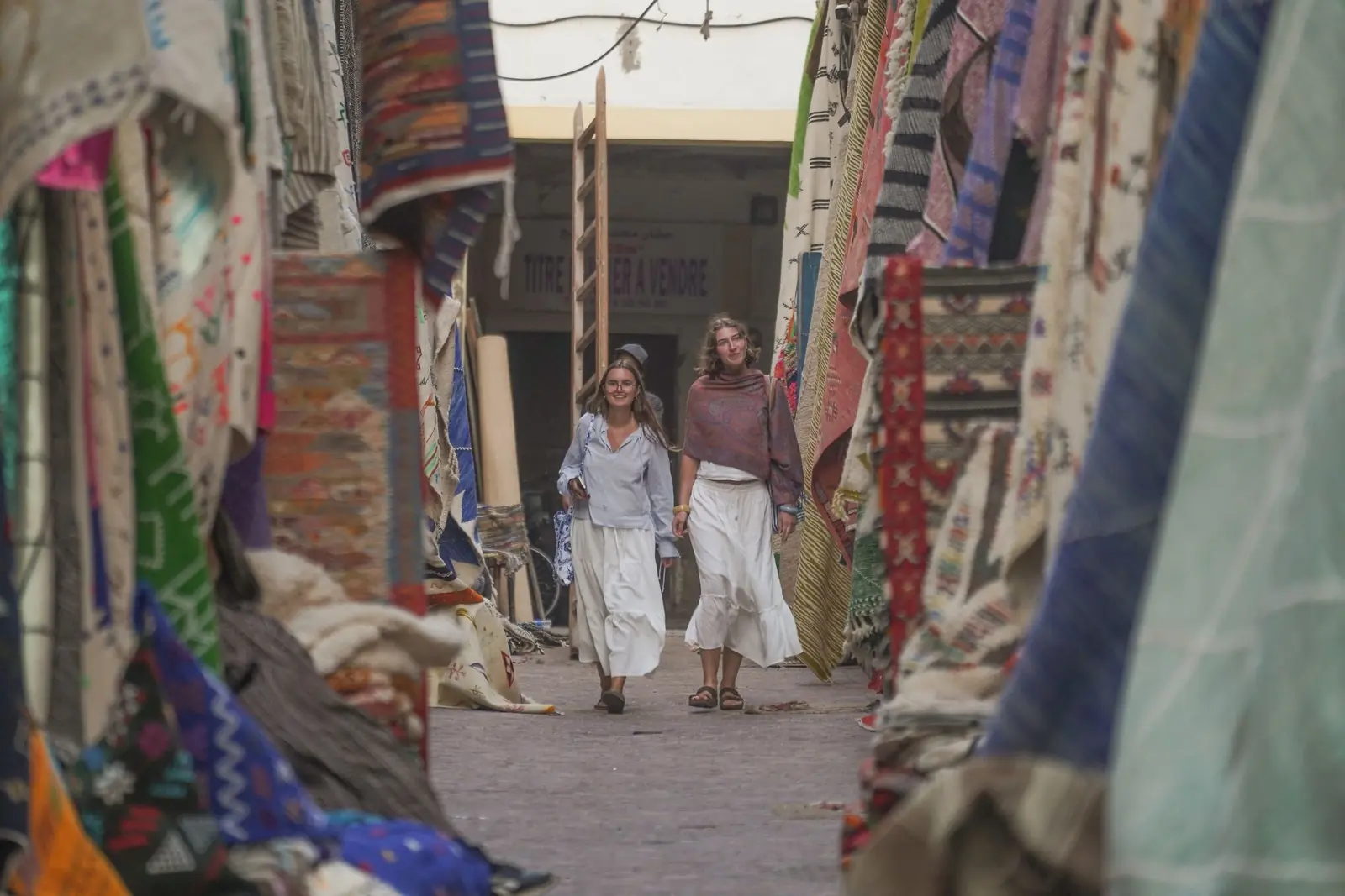 Visitors walking through a souk alley hung with fabrics