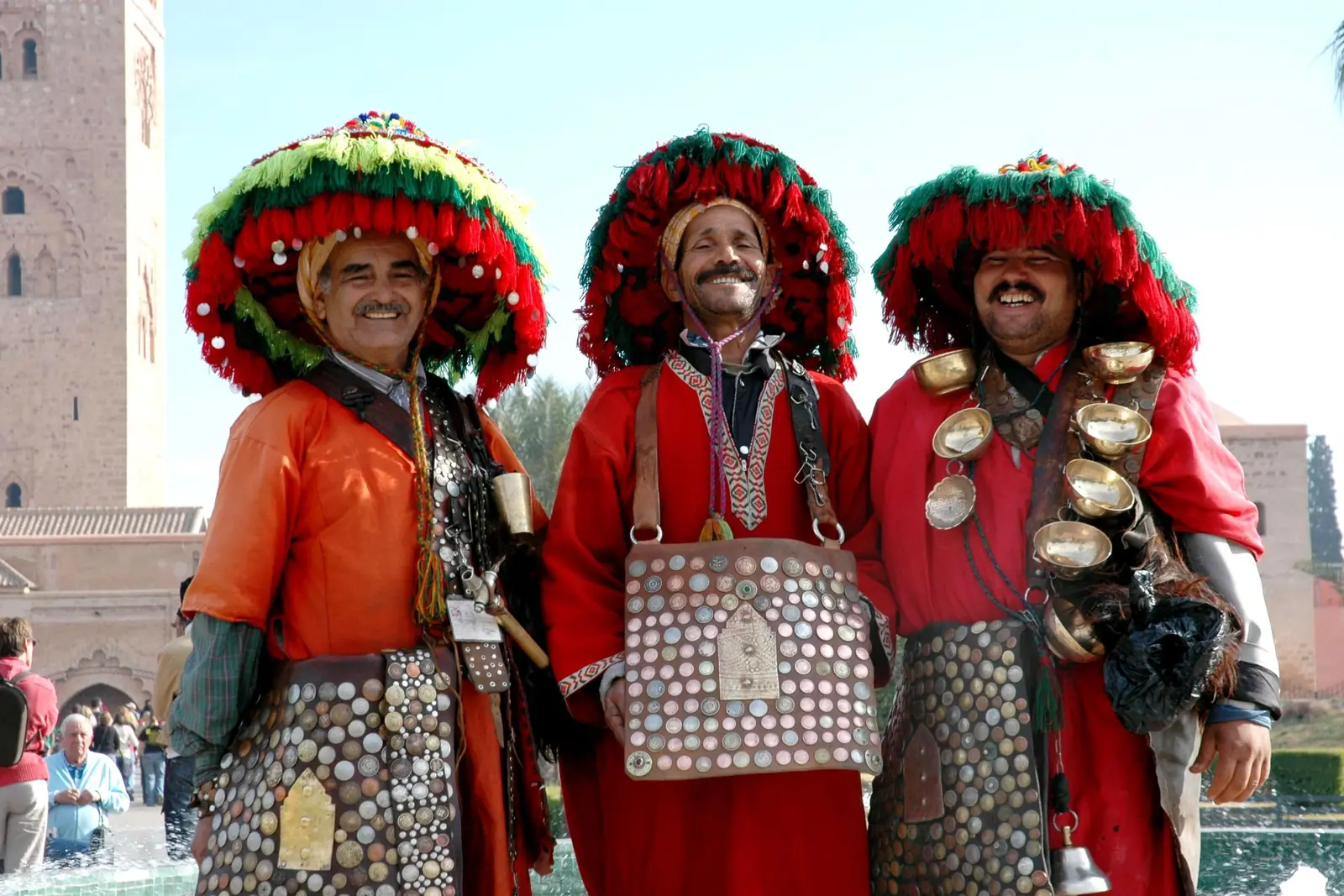 Three water sellers in traditional red costumes and wide hats