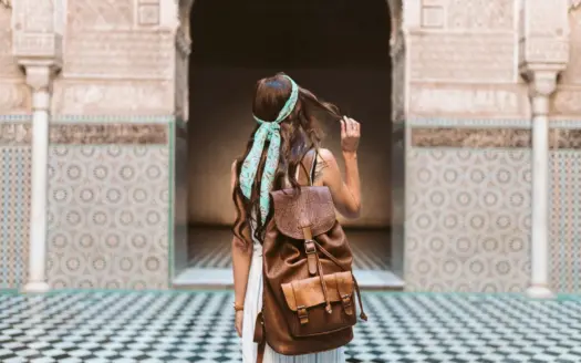 Woman traveller with a backpack in the courtyard of the Ben Youssef Medersa