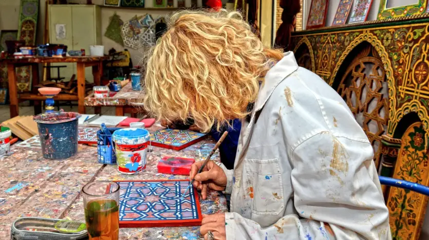 Artisan hand-painting a geometric Moroccan pattern in a crafts workshop