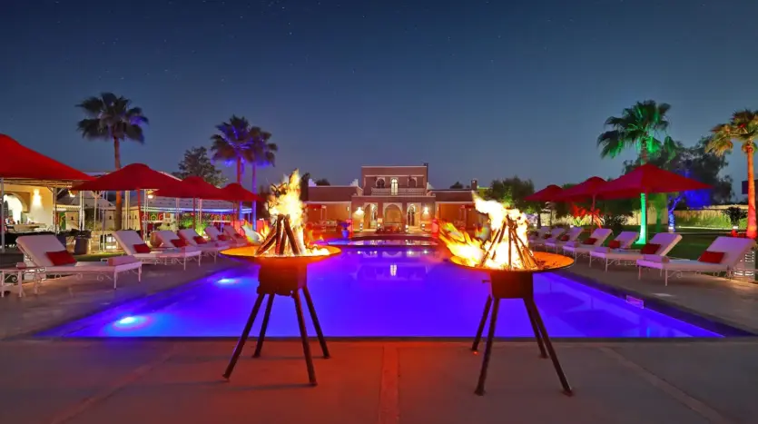 Pool lit at night with fire bowls at Domaine Beldi