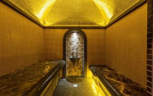 Tiled steam room of a hammam with marble benches and warm light