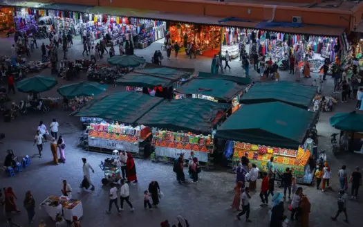 Food and juice stalls under green awnings on Jemaa el-Fna in the evening