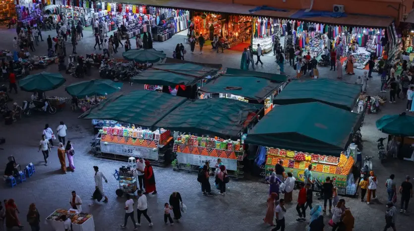 Food and juice stalls under green awnings on Jemaa el-Fna in the evening