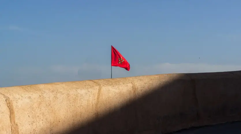 Moroccan flag flying above an ochre rampart under a clear sky