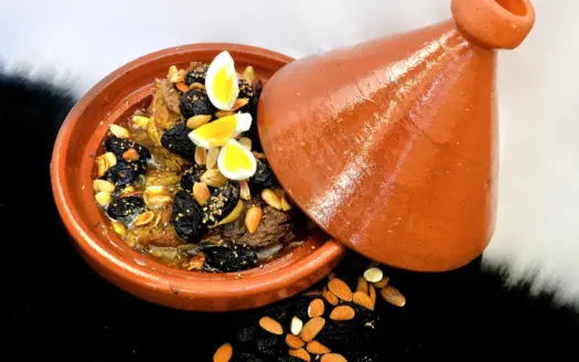 Lamb tagine with prunes, almonds and eggs in a clay tagine dish