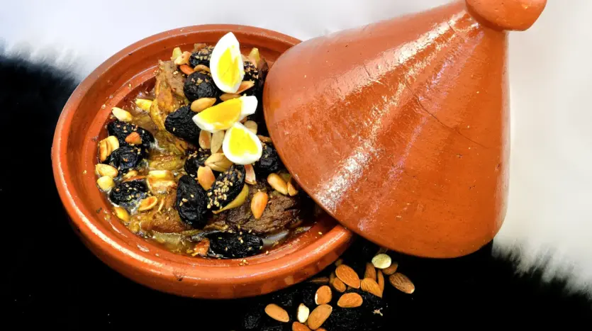 Lamb tagine with prunes, almonds and eggs in a clay tagine dish