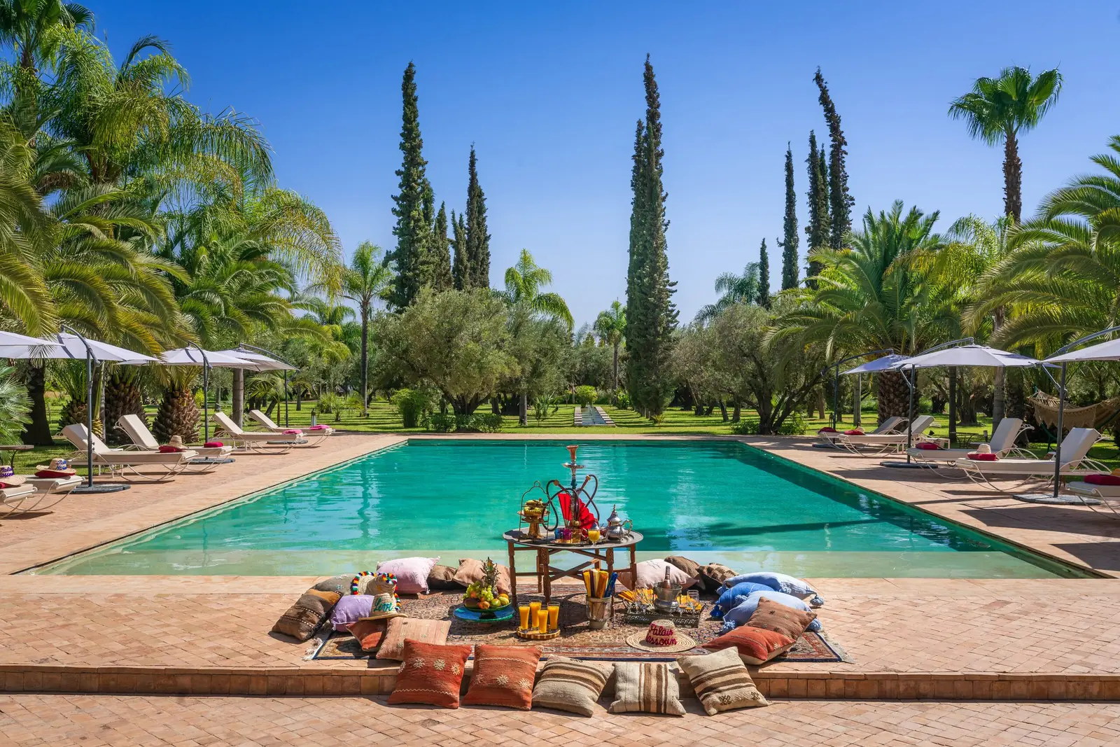 Pool terrace of Palais Mauresque set with floor cushions and parasols