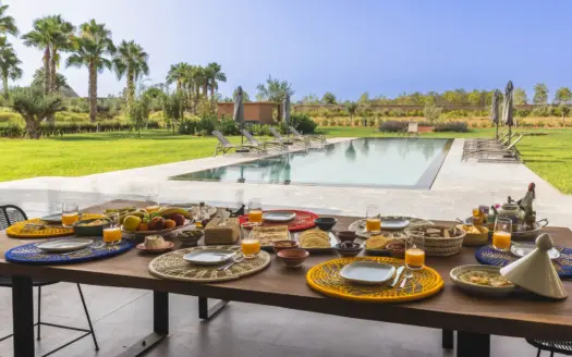 Breakfast table set beside the pool at Villa Dar Tillili