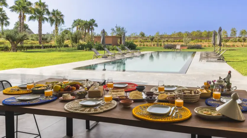 Breakfast table set beside the pool at Villa Dar Tillili
