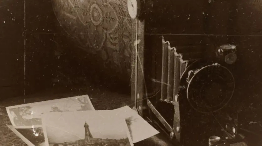 Vintage folding camera beside old black-and-white photographs