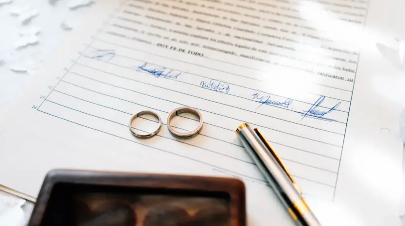 Two wedding rings resting on a signed marriage certificate