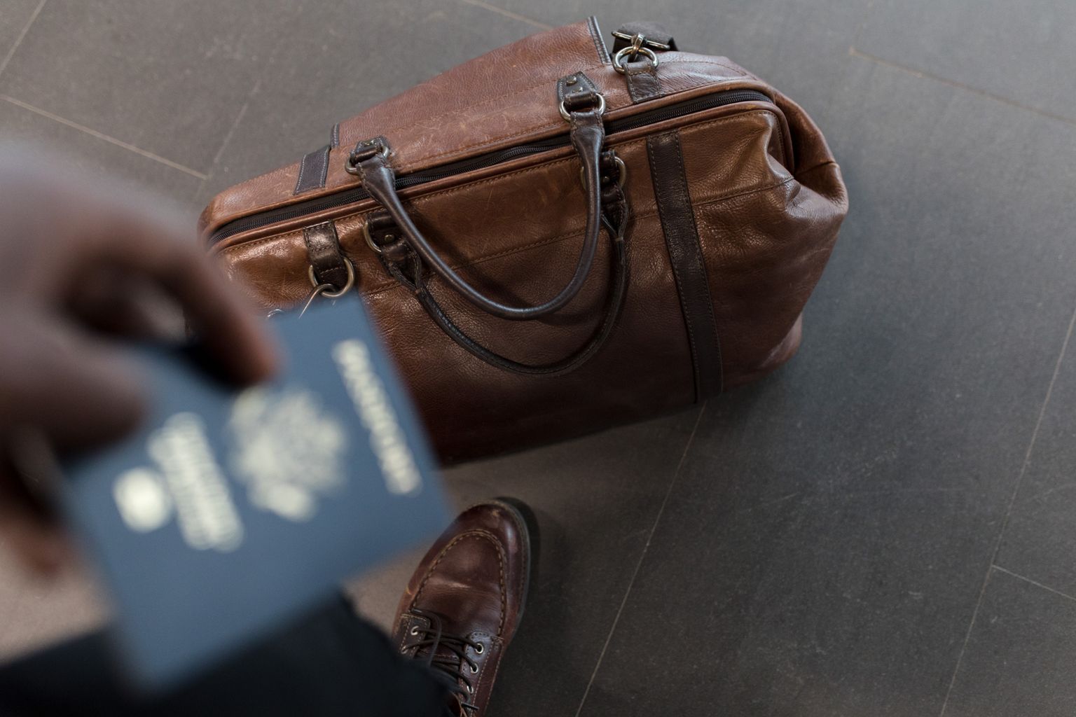 Traveller holding a passport beside a leather holdall before a flight to Morocco